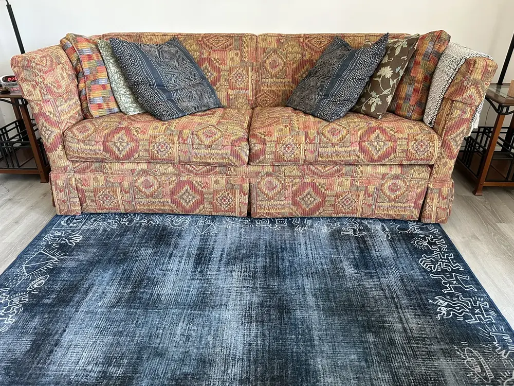 A patterned couch with blue cushions on an indigo rug