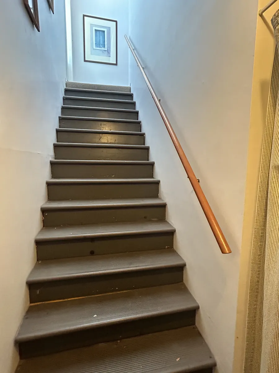 A carpeted staircase with a wooden handrail leading up to the second floor